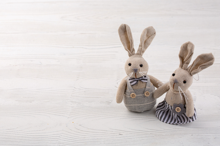 two white rabbits on white wooden background. couple cute Bunny toys. Easter bunnies decoration. Minimal Easter concept. Trendy creative photo. Copy space.の写真素材