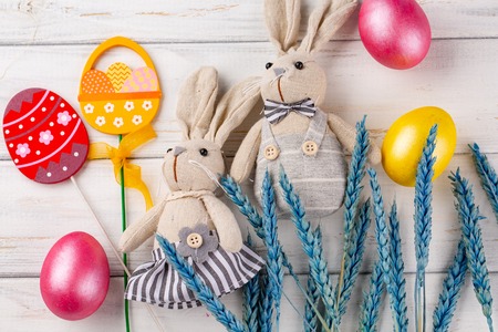 Easter decoration with toy rabbits, eggs on light wooden background