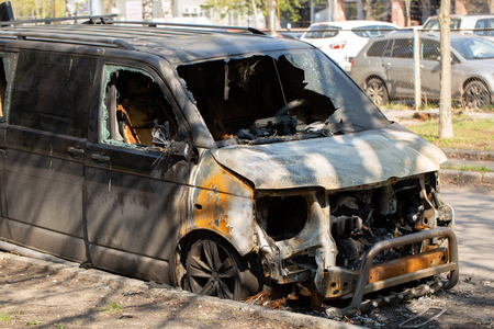 Fully burned minivanor minibus abandoned on the side of a streetの写真素材