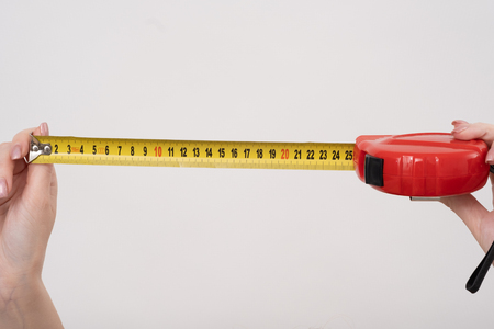 A female hands hold a yellow tape centimeter measure on white, top view at the studio.