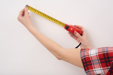 A female hands hold a yellow tape centimeter measure on white, top view at the studio.の写真素材