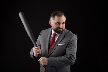 bearded Man in suit and red tie with baseball bat on black backgroundの写真素材