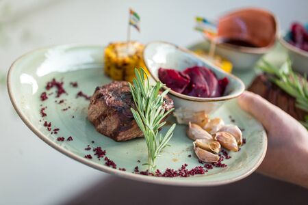 Grilled sliced steak with garlic and rosemary on plate.