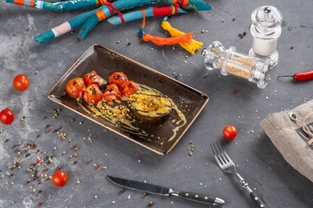 grilled avocado with cherry tomatoes with sauce served on plate. Restaurant dish on stone backgroundの写真素材