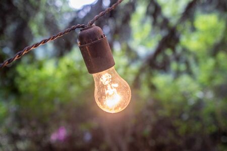 An outdoor lightbulb glowing yellow at dusk.