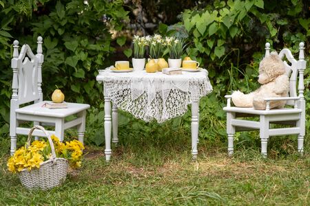 Vintage garden with white tea table and wooden chairs