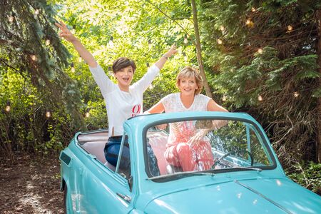 Two women in a vintage car. happy senior mother and adult daughter in a retro convertibleの写真素材