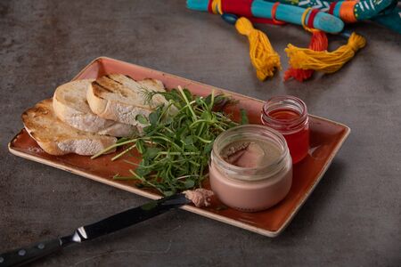 Fresh pate in glass jar with toasted bread on grey tableの写真素材