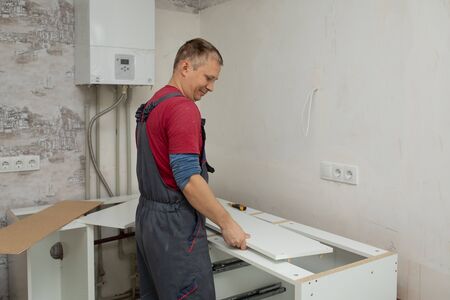 Craftsman kitchen carpenter at kitchen furniture set installation service work. Man during the workの写真素材