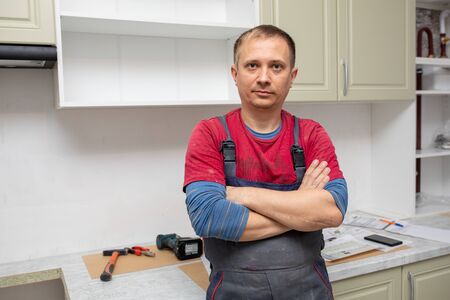 Craftsman kitchen carpenter at kitchen furniture set installation service work. Man during the workの写真素材