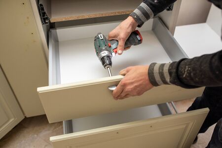 Man using electronic drill to install install furniture handlesの写真素材