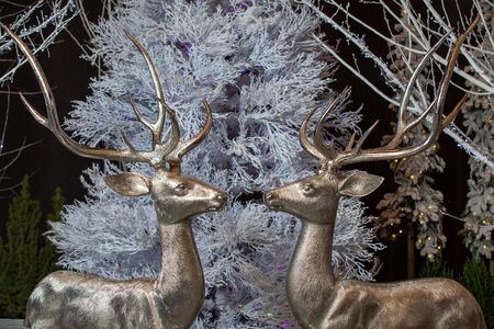 Christmas toys - two figures of glittering deers on the background of a white Christmas treeの写真素材