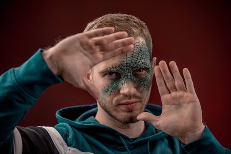 Man with professional horror movie make-up green lizard on dark red