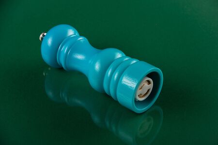 Blue wooden Pepper Mill Shaker lies on a green background
