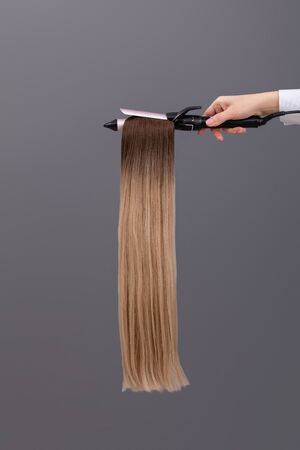 samples of dyed hair. hair cut for hair extensions on grey background. hair tressesの写真素材
