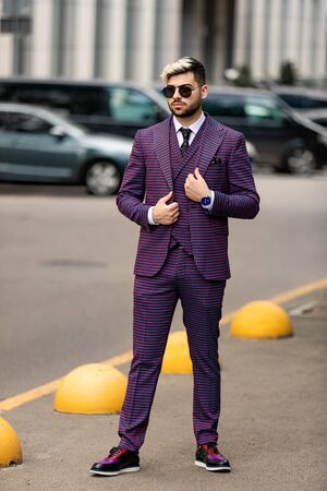 business man in glasses and violet luxery three-piece suit, bow tie posing on the streetの写真素材