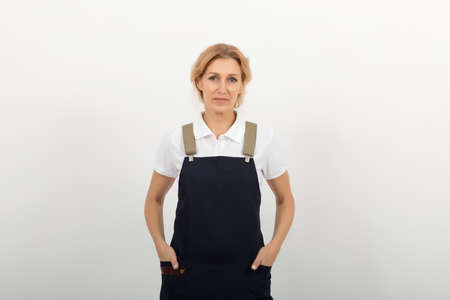 Portrait of woman sales clerk or small shop owner wearing at the apron standing on light background. cleaning agency provides its servicesの写真素材