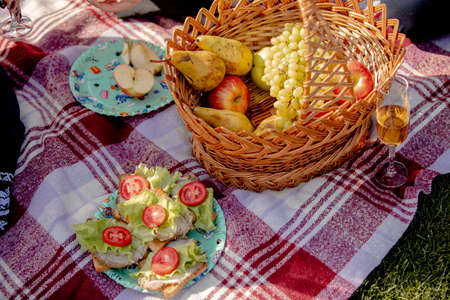 Picnic basket on green lawn. still life of sandwiches, fruits and a glass of wineの写真素材