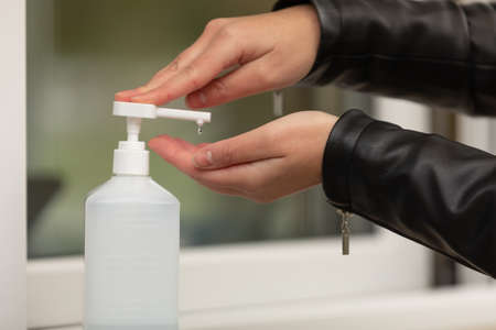 Female hand pressing bottle and pouring alcohol-based sanitize on hands. Disinfection concept....