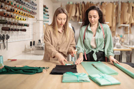 Two Young fashion designers or tailors in packing new clothes in before delivering in workshop studioの写真素材