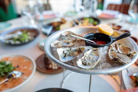 platter of fresh organic raw oysters on ice at restaurant. Oysters on the server tableの写真素材