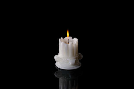 White candle lit burning on black background. antique column candleの写真素材