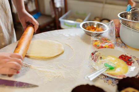 woman rolling out dough with rolling pin in kitchen. woman rolls out dough for Easter cakes