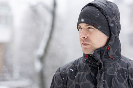 Portrait of European Man Standing in WInter outdoor. Snowy Winter Day in the city. Copy space for text.の写真素材