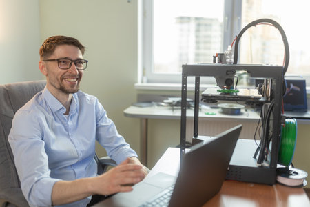 Engineering student working in the lab with a laptop, 3D printer in the background