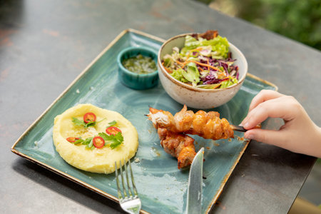 Mashed potatoes, chicken kebab, salad. Children's menu in the restaurant. Child's hand holding a barbecueの写真素材