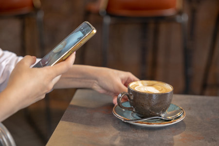 Young girl using Photography of smartphone of latte art coffee on mobile camera display while...