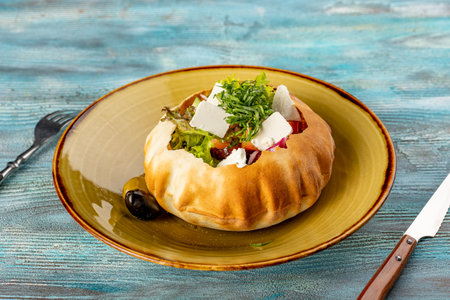 fresh vegetable salad with feta in bread - Healthy food style. Original restaurant serving in bread instead of a plate on blue wooden backgroundの写真素材