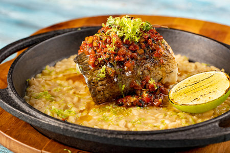 A piece of fish with sauce on a bed of rice or barley, grilled with lime. Original dishes from the chef of the restaurantの写真素材