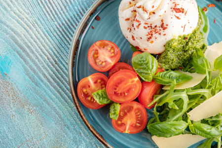 A dish of mozzarella cheese, basil, parmesan, pesto and tomatoes. restaurant serving