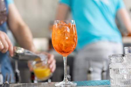 Classic Italian Aperol Spritz cocktail standing on the bar on the background of the bartenderの写真素材