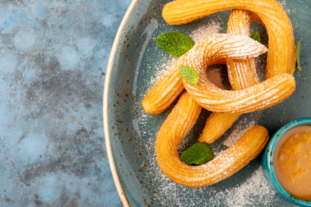 Churos spanish dessert decorated with icing sugar on a wooden board. Gray textured background. Beautiful serving dishes. Dessert.の写真素材