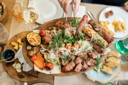 Assorted different types of grilled meat. Pork shish kebab, lamb rack, pork rack, lulakebab and grilled vegetables with greens, lie on a large pita breadの写真素材