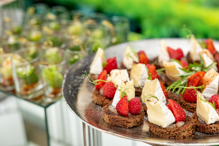Canapes with brie cheese, raspberry and strawberries. The concept of restaurant buffet catering...