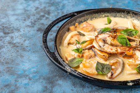 Creamy seafood casserole pot shrimps, squid calamari, fish fillet, colored bell pepper slices and white sauce of flour, milk and ghee cooked in the oven, sea food mixtureの写真素材