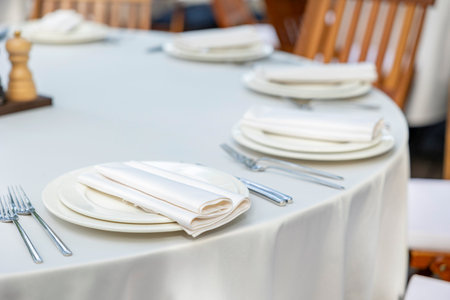 Beautifully organized event - round served table banquet ready for guests, round decorated table with empty plate, glasses, forks, napkin. Elegant dinner tableの写真素材