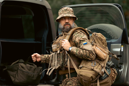 Portrait of a military man dressed in uniform. The military man takes his things from the trunk of...