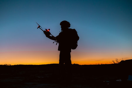 Silhouettes of soldiers are using drone for scouting during military operation against the backdrop of a sunset. Application of modern technology during warの写真素材