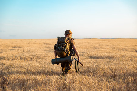 military man with a backpack in the field. Soldier goes on a mission. Back viewの写真素材