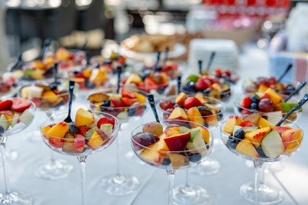 Bride and groom sitting at a table on which there is a plate of fruit. fruit salad presented at a buffet or cateringの写真素材