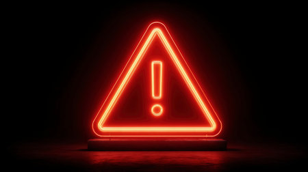 A glowing red neon triangle with an exclamation mark inside, set against a stark black background, symbolizing danger or warning.の素材