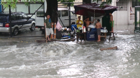 People trying to protect themselves from the flood waters  Flooding in Quezon City despite of drainage repair  Overflowing drainage canal after almost an hour of heavy downpour in Quezon Cityのeditorial素材