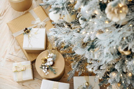 Christmas gifts under a christmas tree decorated with golden balls and garlands. Selective focus, shallow depth of field, top viewの写真素材