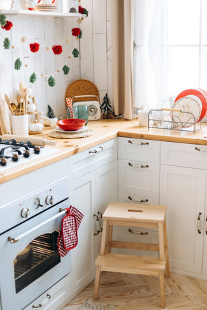 Festive kitchen corner with white cabinets and wooden countertops. Christmas decor includes red and...