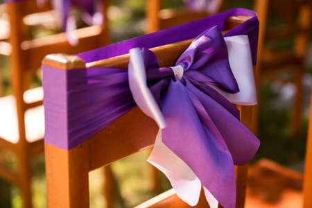 In the photo we see chairs decorated with lavender lilac ribbons. Outdoor wedding ceremony. Lavender-style location prepared.の写真素材