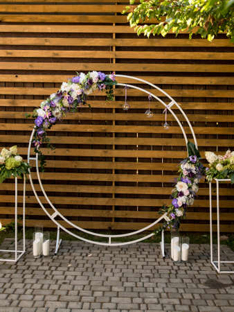 Area of the wedding ceremony. Round arch with fresh purple flowers. Cute, trendy rustic decor. Part of the festive decor, floral arrangement.の写真素材